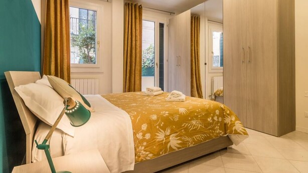 A bedroom with a bed, a nightstand, a lamp, and a wardrobe. - Porpora Home@ Venice (Venice)