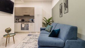 A modern living room with a blue sofa, a small round table with a globe, and a patterned rug. - Porpora Home@ Venice (Venice)