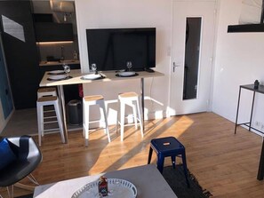 Un espacio habitable moderno con comedor, televisor y una pequeña zona de estar.