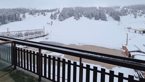 A snowy landscape with a ski lift and a building in the distance.