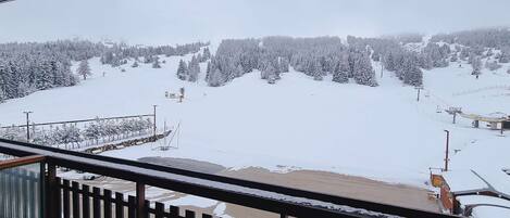 Schneebedeckte Landschaft mit einer Seilbahn und einem Gebäude in der Ferne.