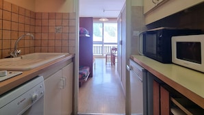 A compact kitchen with a Bosch dishwasher, a microwave, and a sink with a faucet.