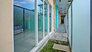 A narrow corridor with glass doors and windows, a stone wall, and a tiled floor. - Capital O 92670 Borobudur Homestay (Banyuwangi)
