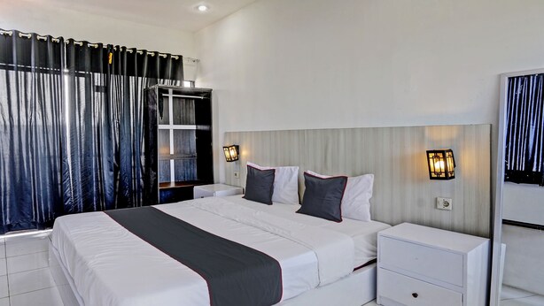 A modern hotel room with a large bed, two bedside tables, a wardrobe, and a mirror. - Capital O 92670 Borobudur Homestay (Banyuwangi)