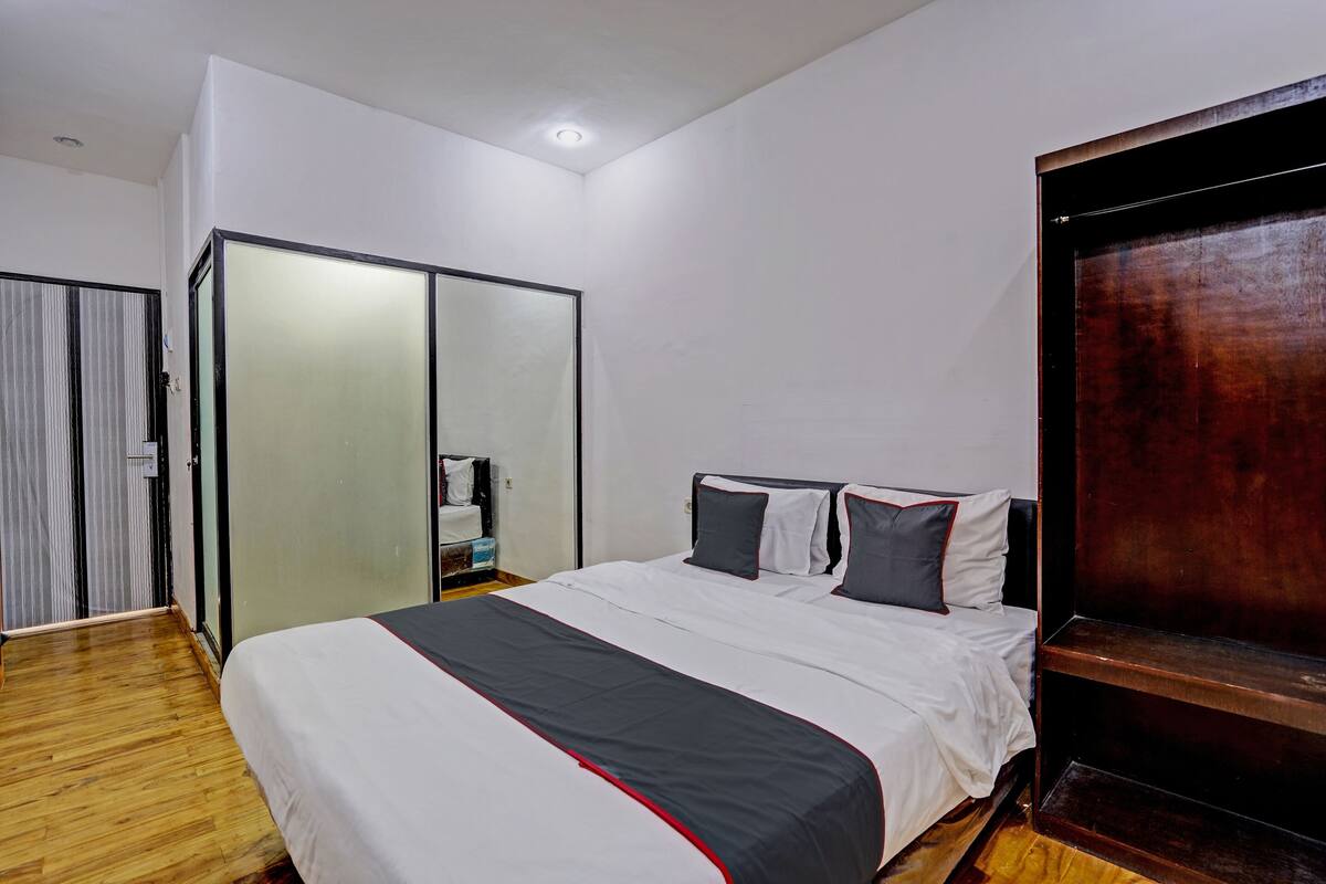 A bedroom with a bed, a wardrobe, and a mirror.