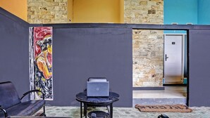 A room with a stone wall, a door with a number, a laptop on a small table, and a chair. - Capital O 92670 Borobudur Homestay (Banyuwangi)