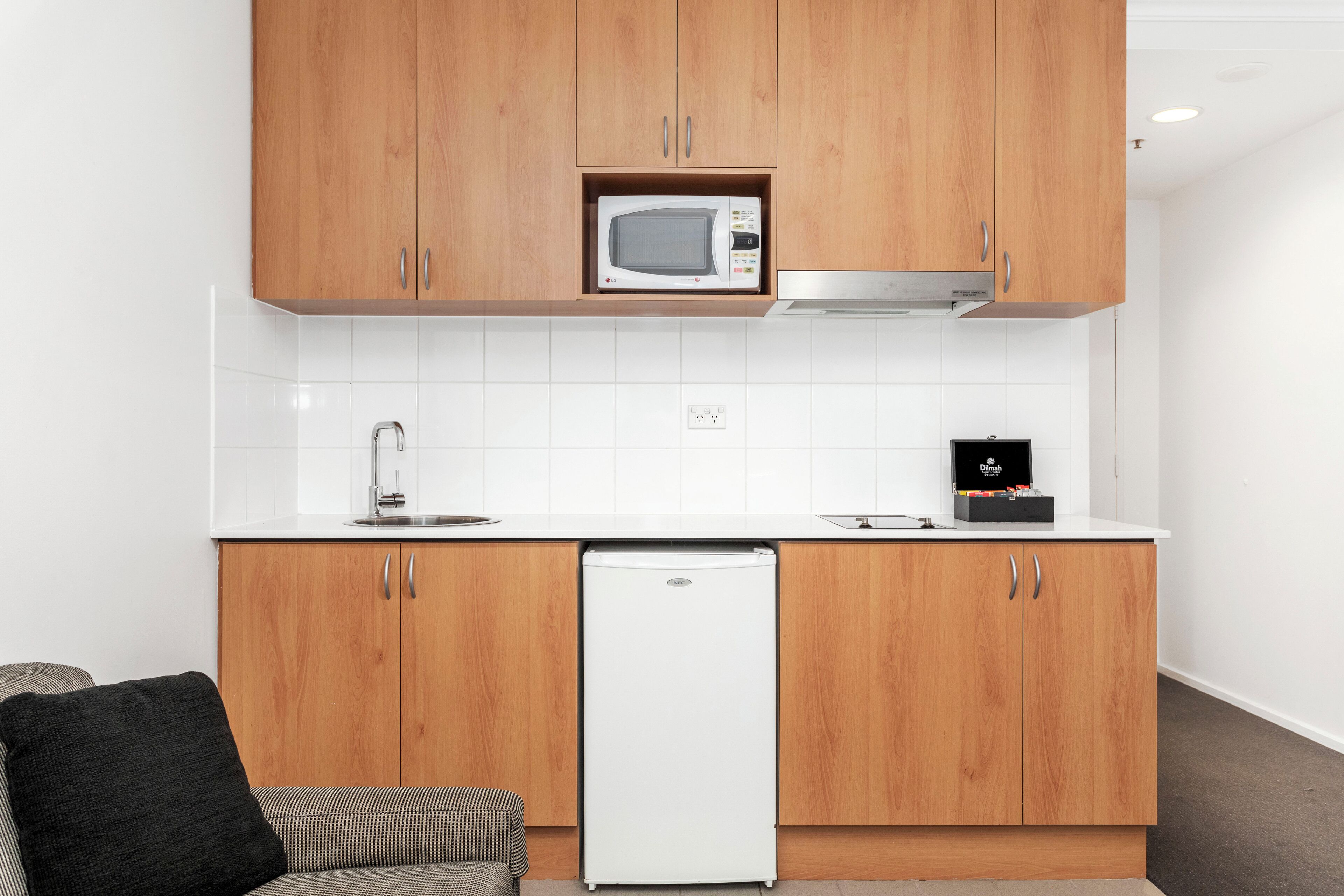 A modern kitchen with wooden cabinets, a built-in microwave, a dishwasher, and a coffee machine.