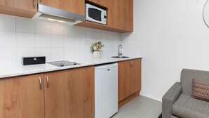 Ett modernt kök med träskåp, en vit bänkskiva, en inbyggd mikrovågsugn, en diskho och en diskmaskin.