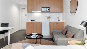 Ett kompakt bostadsutrymme med ett litet kök, en matplats och en sittgrupp med en soffa och ett soffbord.