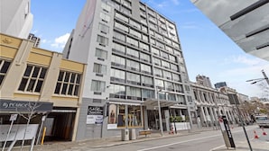 Ett hotell med flera våningar, en modern fasad, stora fönster och en överbyggd entré.