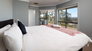 A bedroom with a large bed, a balcony with a table and chairs, and a view of the outdoors. - Divine Views on Roper - Glorious three bedroom, two bathroom townhouse with views to die for! (Albury)
