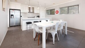 A modern kitchen with white cabinetry, a built-in island, and pendant lighting. - Divine Views on Roper - Glorious three bedroom, two bathroom townhouse with views to die for! (Albury)