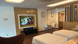 Une chambre d’hôtel équipée d’une télévision, de deux lits, d’un bureau et d’un petit coin salon.
