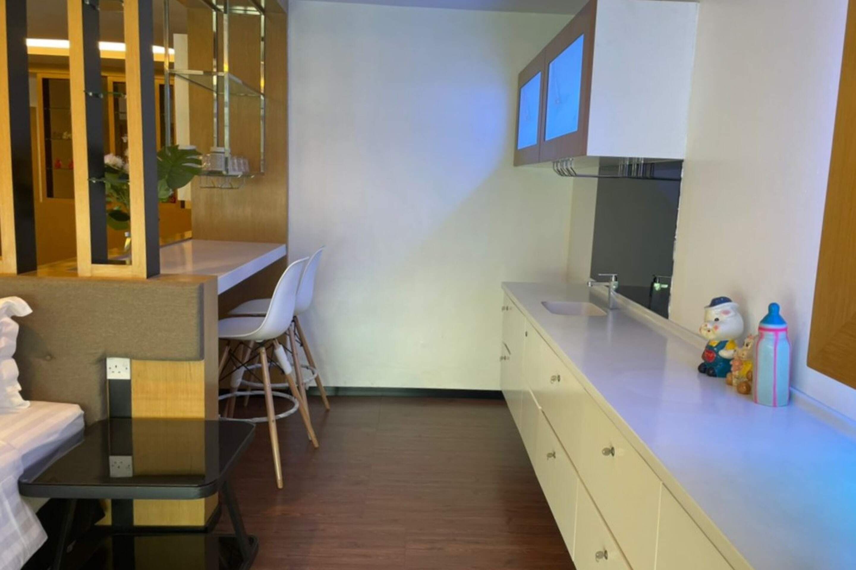 Une chambre d’hôtel compacte comprenant une petite kitchenette, un coin repas avec une chaise, un lit et un miroir au-dessus du comptoir.