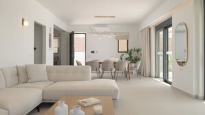 Una sala de estar moderna con un sofá modular, una mesa de centro de madera y un comedor con mesa y sillas.