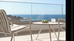 Un balcón con mesa, dos sillas y vista al océano.