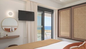 Un dormitorio con cama, televisor, espejo, ventana con vista al mar y balcón.