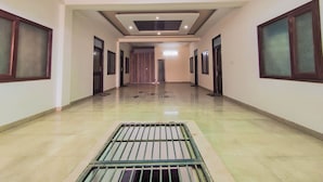 Un amplio pasillo con tragaluz, puertas a ambos lados y un desagüe central.