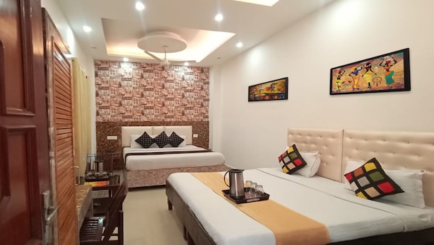 Habitación de hotel con cama, mesitas de noche, ventilador de techo y obras de arte en las paredes.