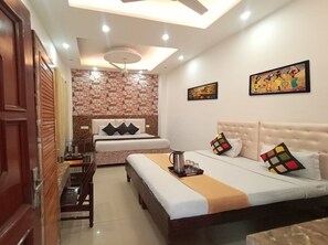 Une chambre d’hôtel avec un lit, des tables de chevet, un ventilateur de plafond et des œuvres d’art accrochées aux murs.