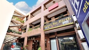 Un hotel llamado "Hotel Re-Birth" con un letrero, una escalera y un coche aparcado en la entrada.