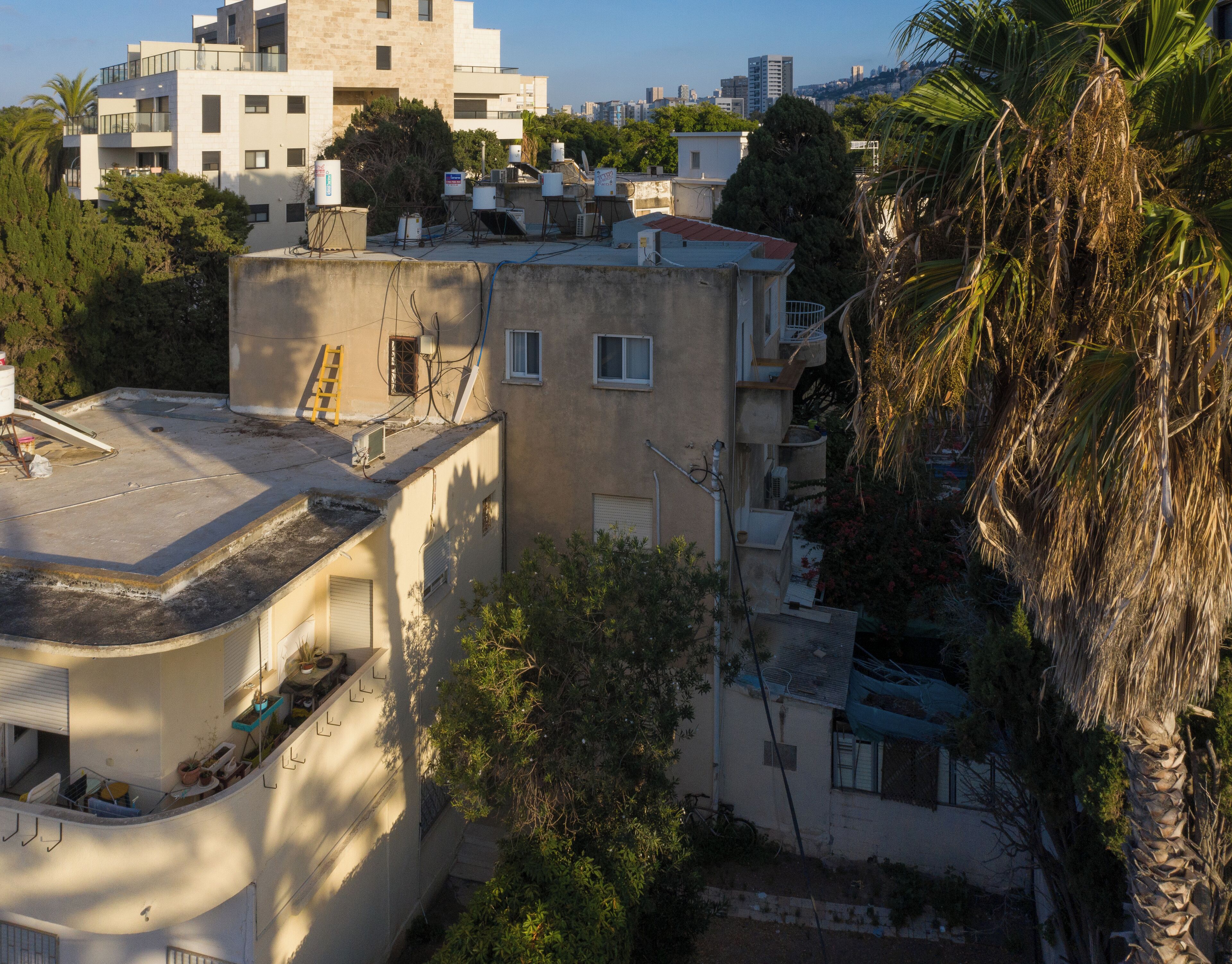 A residential building with multiple balconies, a ladder, and various outdoor equipment.