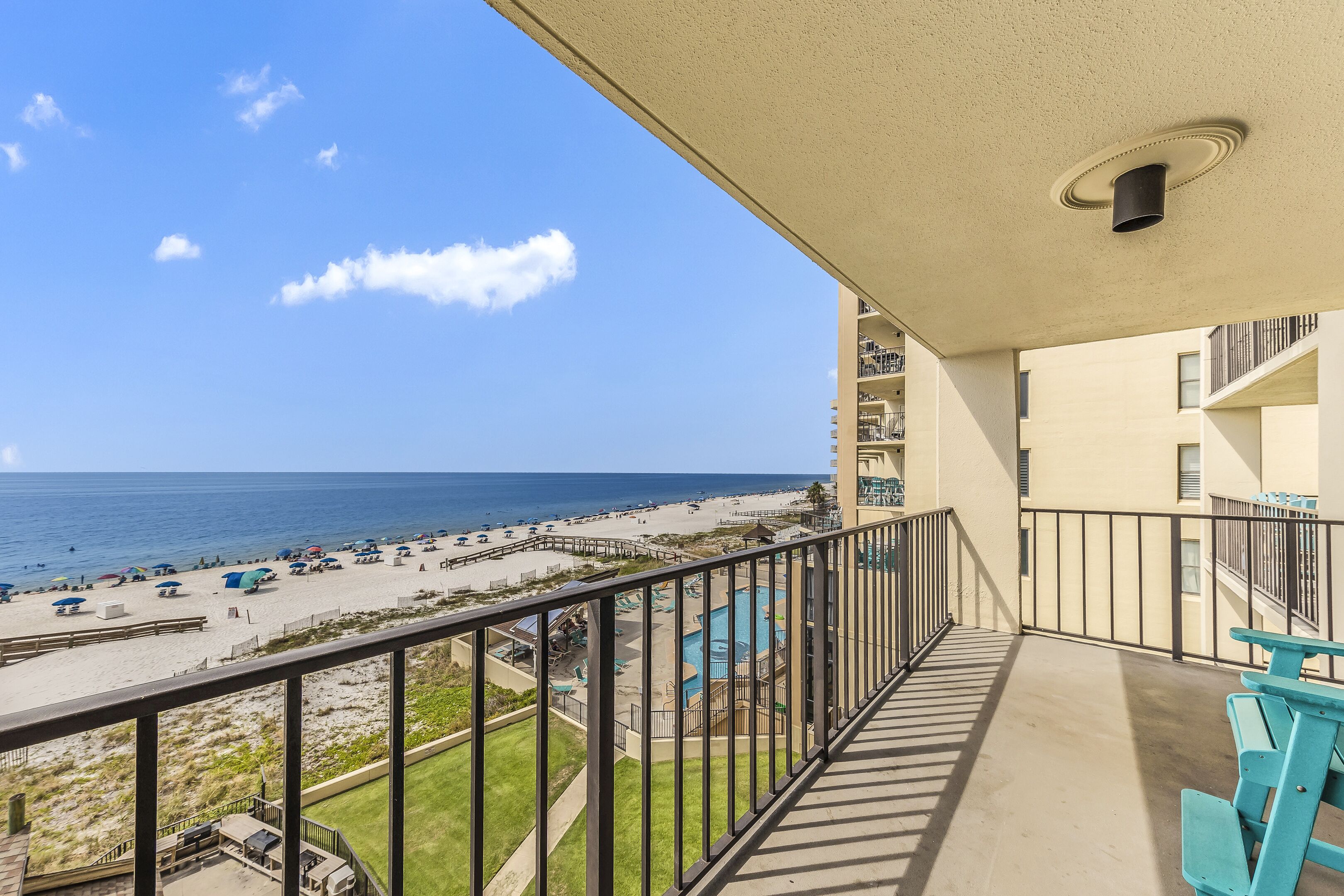 A balcony with a view of a beach and a pool area.