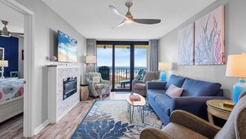 Ein modernes Hotelzimmer mit Balkon, Deckenventilator, großem Fenster und blauem Sofa.
