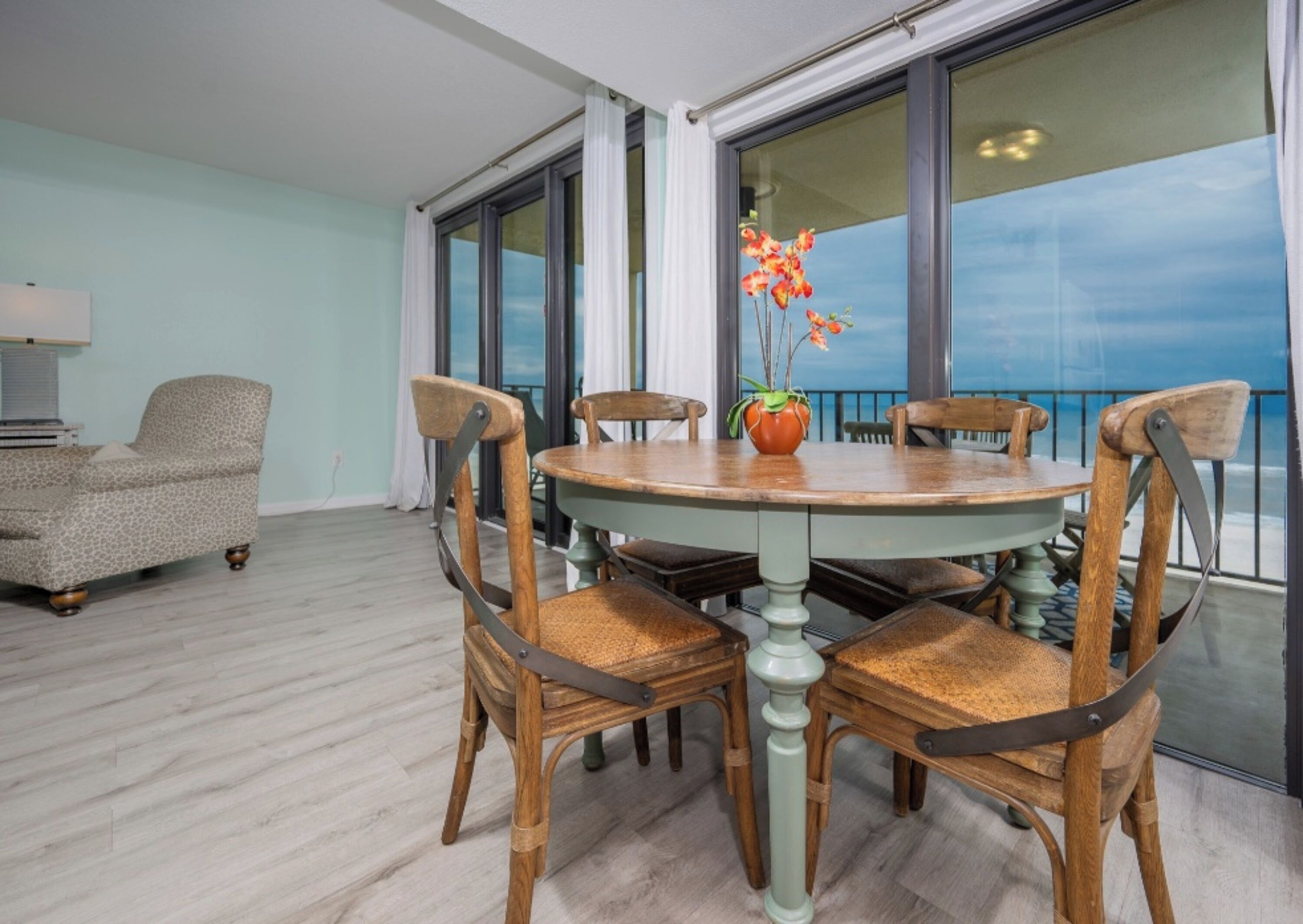 A dining area with a round table, four chairs, and a vase of flowers.