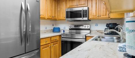 A kitchen with stainless steel appliances, wooden cabinets, a toaster, and a sink.