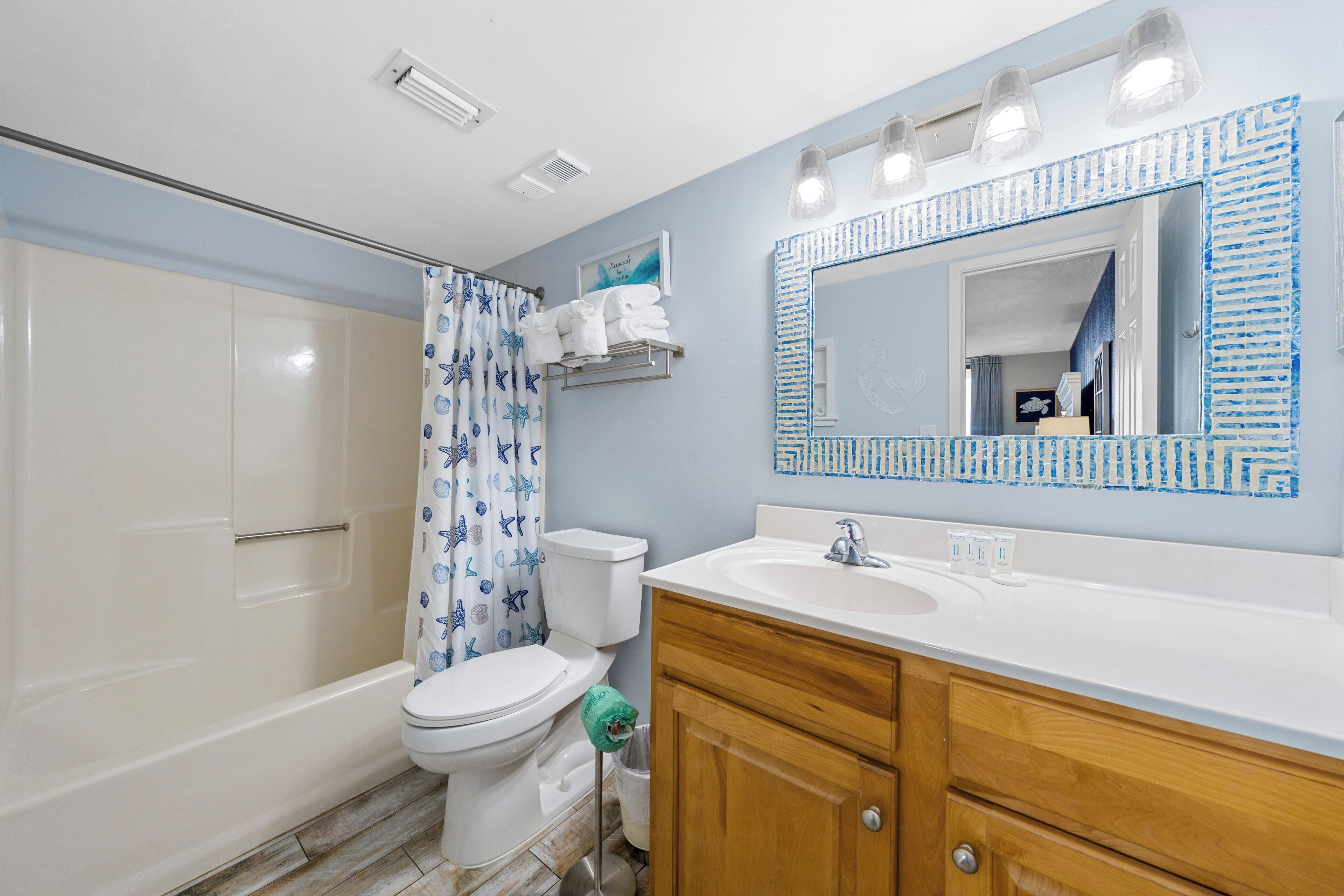 A bathroom with a shower, toilet, sink, and vanity.
