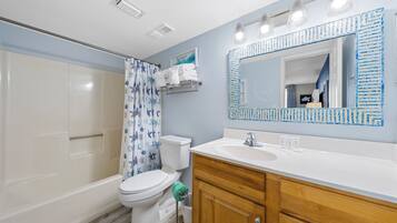 A bathroom with a shower, toilet, sink, and vanity.