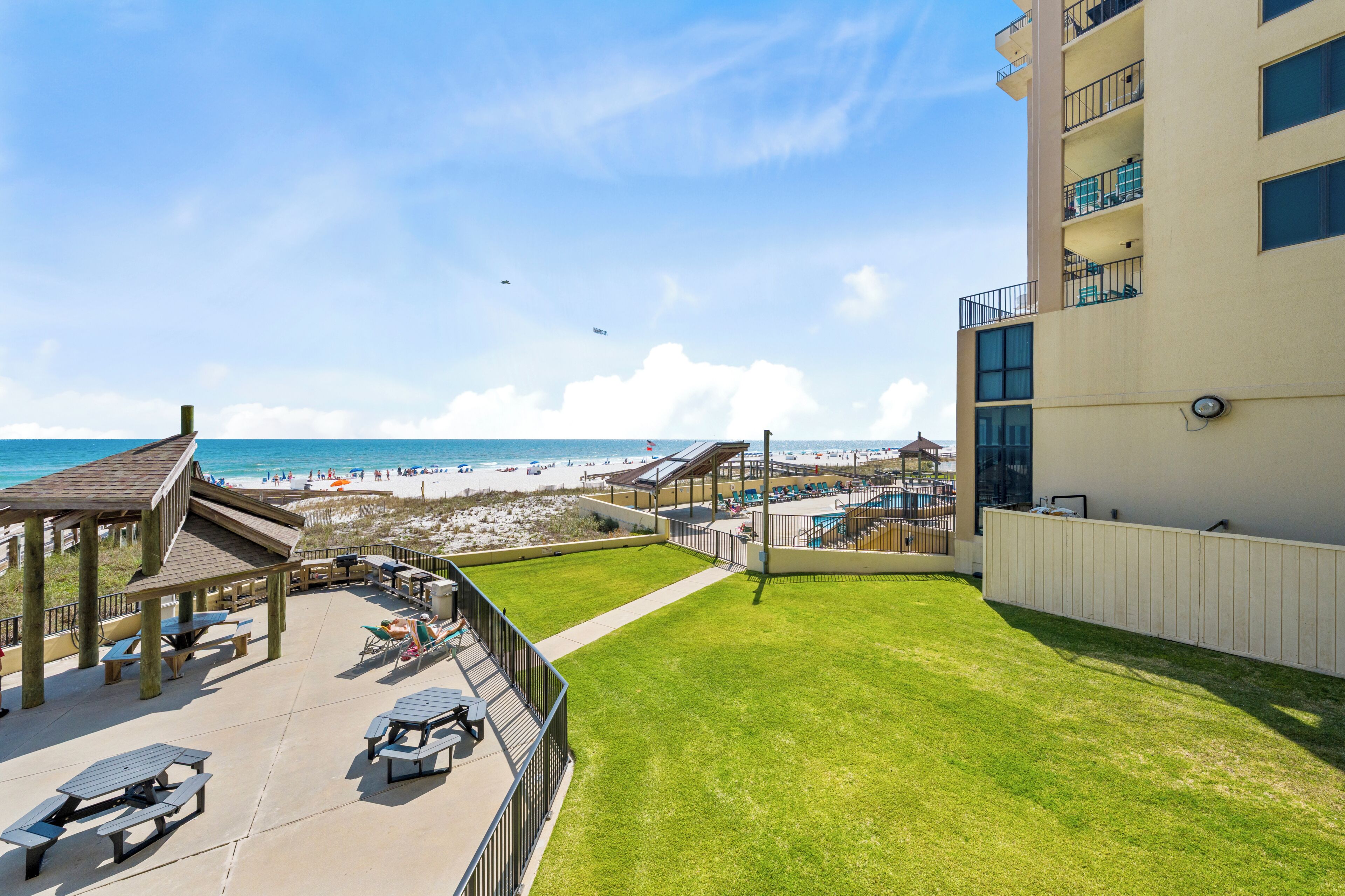 Eine Dachterrasse mit Blick auf den Strand, einen Pool und ein Gebäude mit Balkonen.