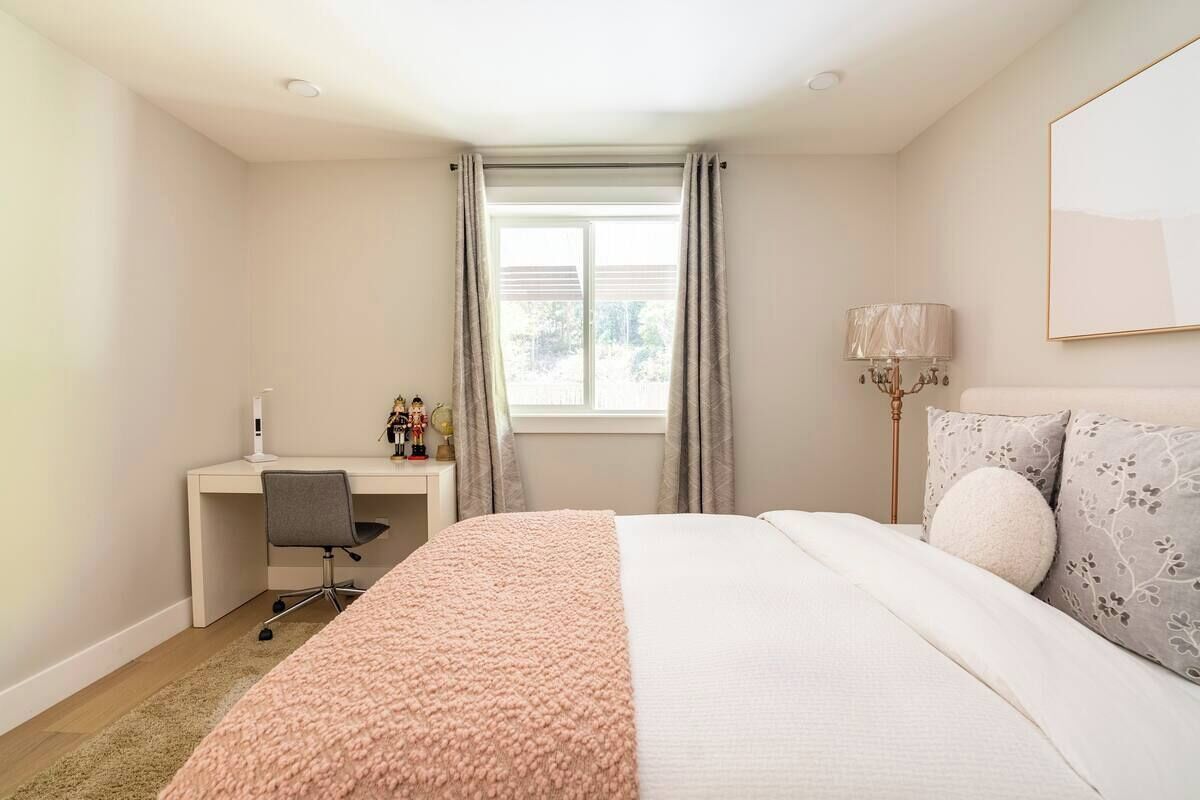 A bedroom with a bed, a desk, and a chair.