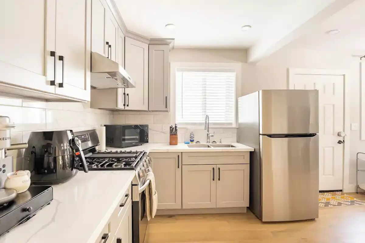 A modern kitchen with white cabinets, a stainless steel refrigerator, a microwave, and a stove.