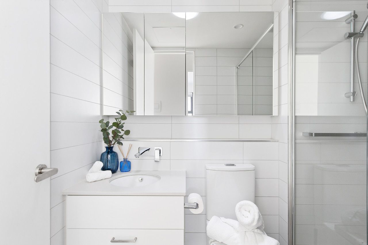 A modern bathroom with a white sink, mirror, and toilet.