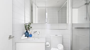 A modern bathroom with a white sink, mirror, and toilet.