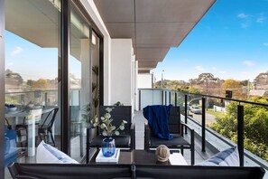 A balcony with a dining table, chairs, and a vase of plants. - Caulfield Elegance: Chic Abode (Caulfield North)
