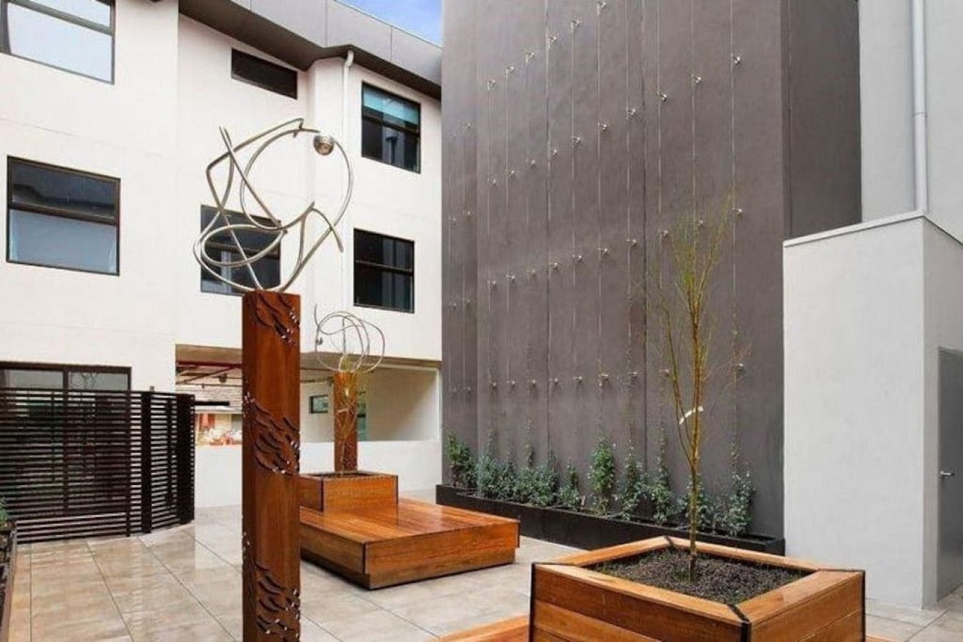 A modern outdoor area with a seating area, a decorative metal sculpture, and a vertical garden wall.