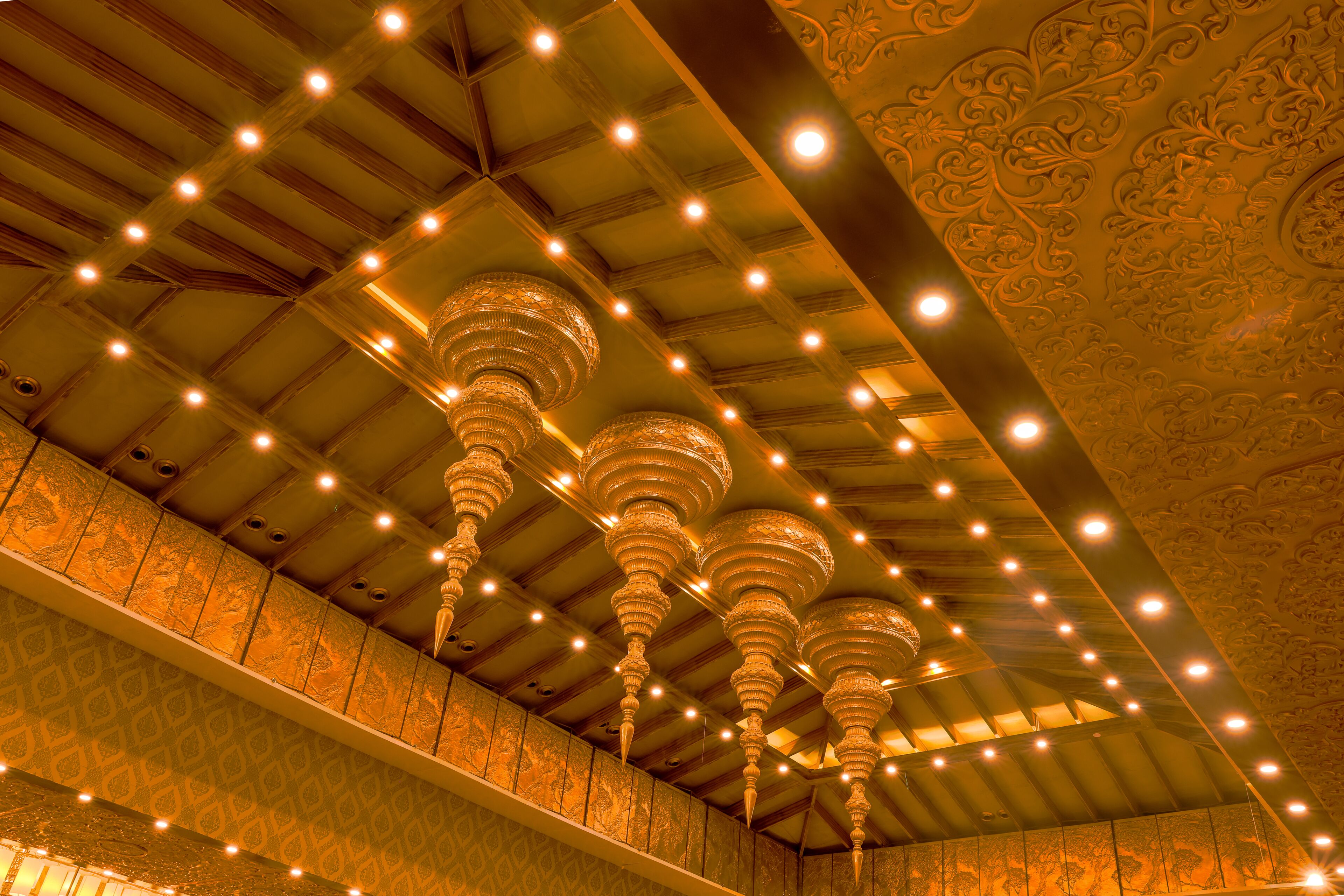 A ceiling with ornate chandeliers and patterned wall designs.