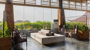 Un espacio lounge moderno con sofá, sillas y una mesa de madera.
