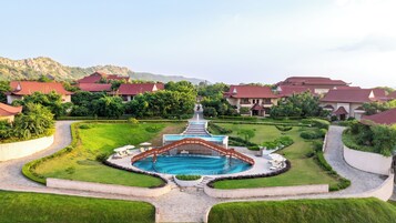 A resort with a central pool, manicured gardens, and traditional-style buildings.