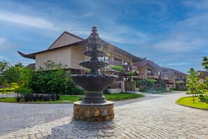 Ein Steinbrunnen in einem Innenhof, im Hintergrund ein mehrgeschossiges Gebäude.