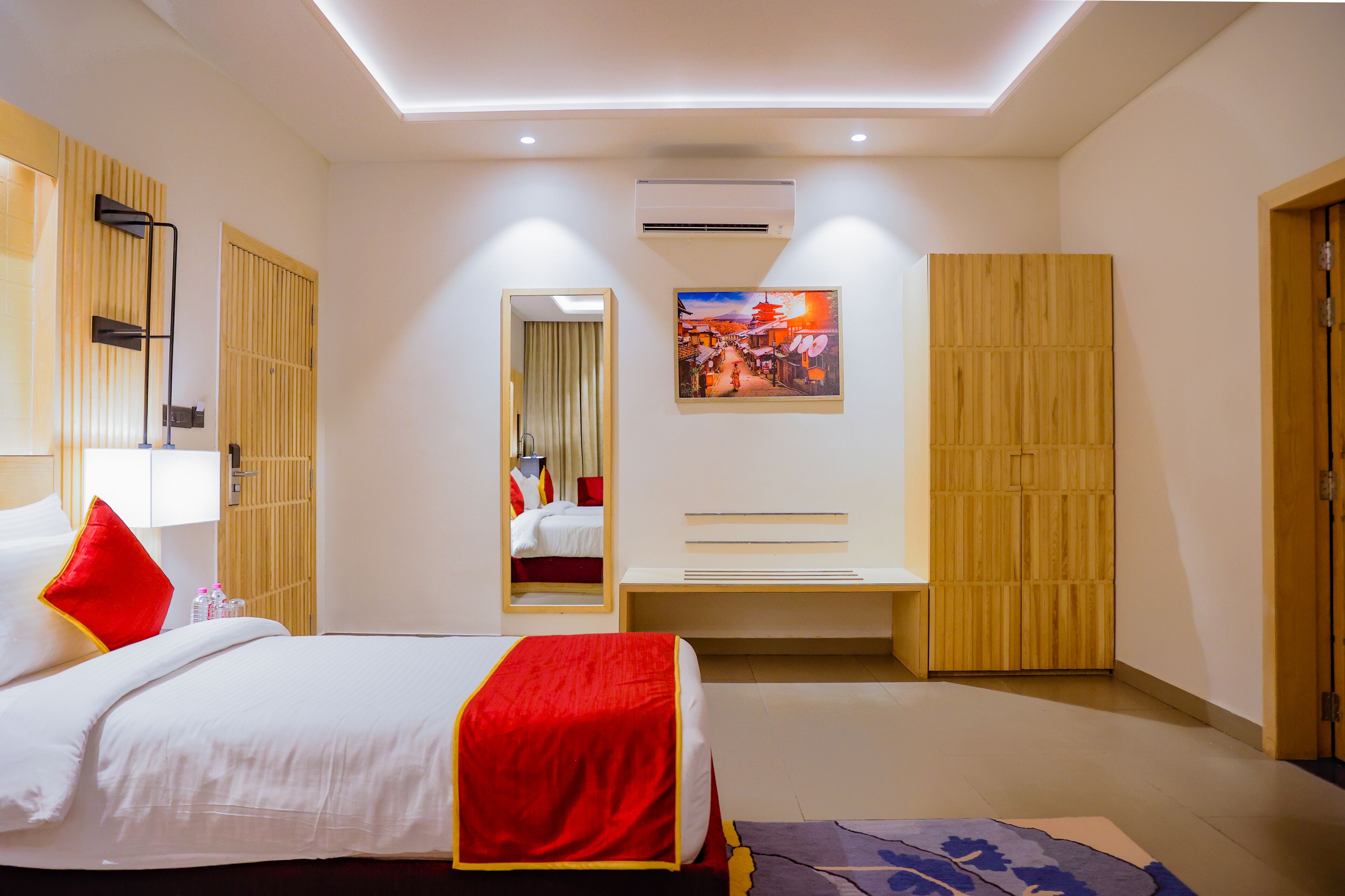Ein Hotelzimmer mit Bett, Nachttisch, Spiegel, Kleiderschrank und einem Bild an der Wand.