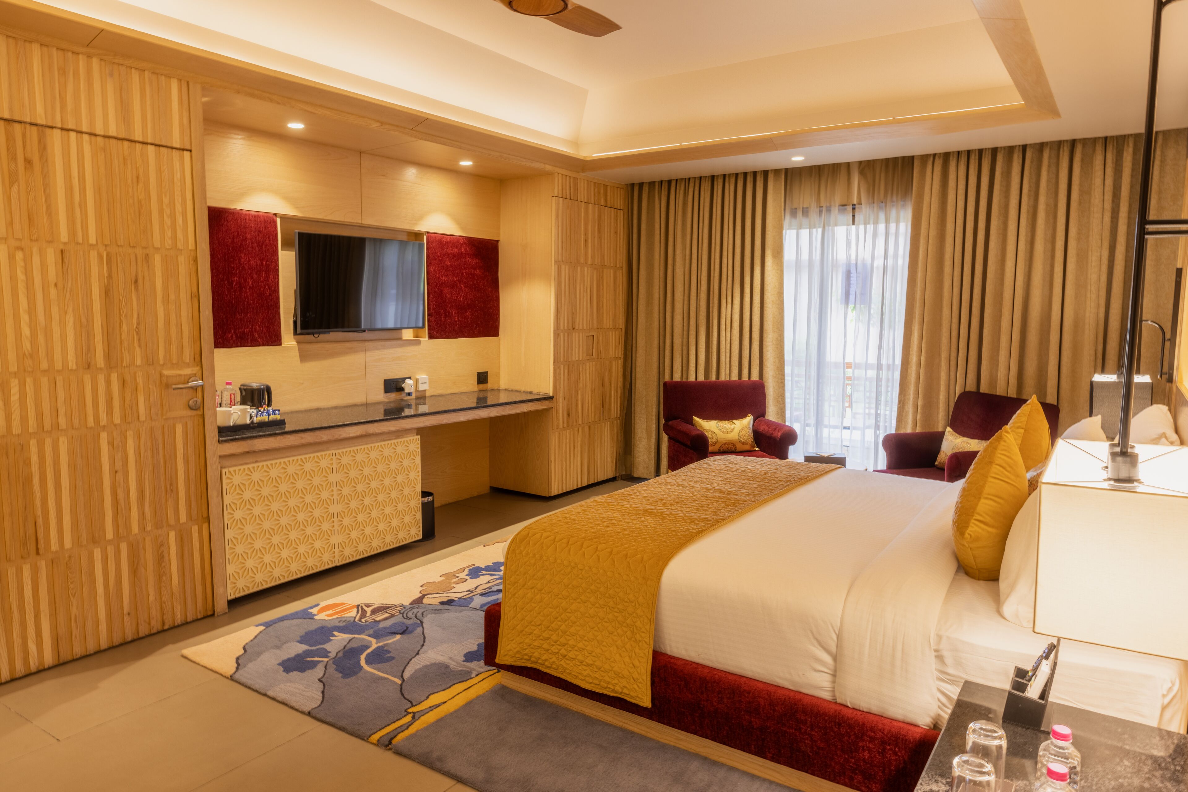 A hotel room with a large bed, a desk, a chair, a TV, and a bathroom.