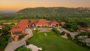 Vista aérea de un resort con varias construcciones, un patio central y exuberante vegetación circundante.