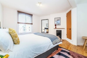 Relax in this serene bedroom with a large bed, window with blinds, and a mirror above.