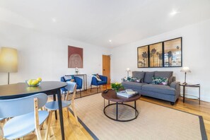 Uma sala de estar moderna com sofá, cadeiras, mesa de centro e obras de arte nas paredes.