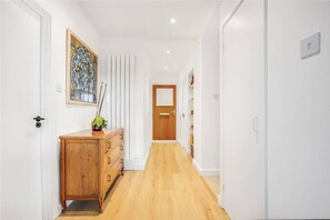Stylish hallway with a cabinet, artwork, and potted plant.