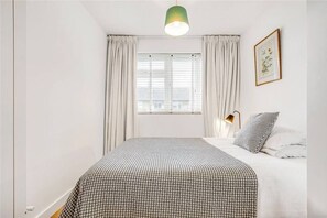 Relax in this inviting bedroom with a large bed and a bedside lamp, featuring a framed picture on the wall.
